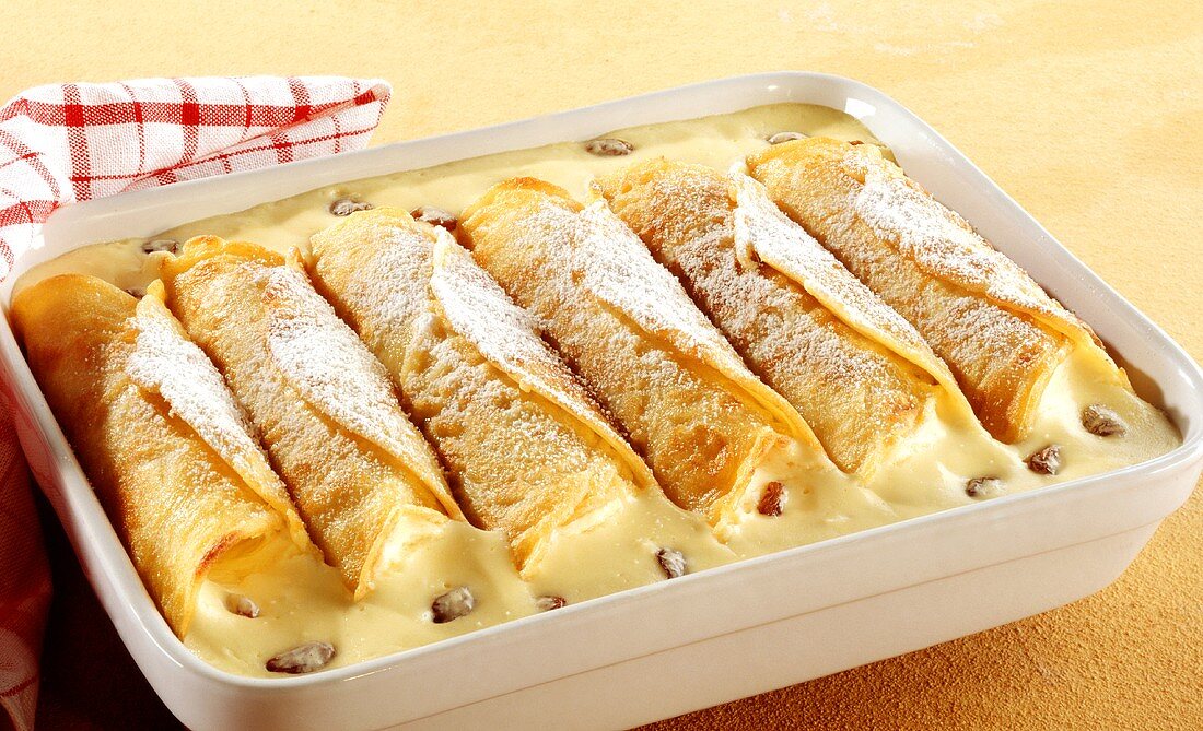 Crepes with vanilla cream and raisins in baking dish
