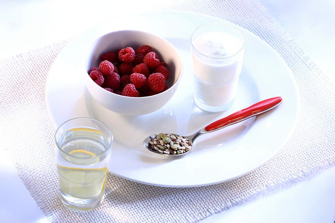 Diätfrühstück mit Himbeeren, Joghurt, Cerealien und Wasser