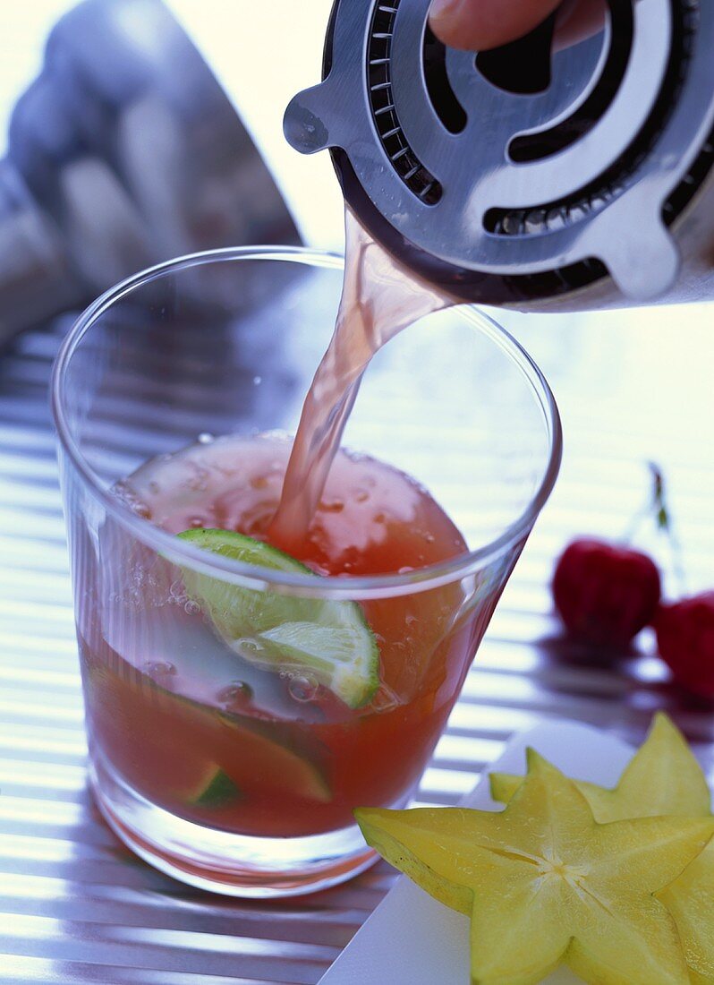 Cocktail with cherry juice and lime wedges