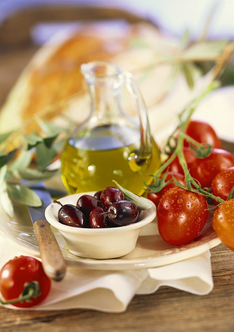 Stillleben mit Oliven, Tomaten, Olivenöl und Brot