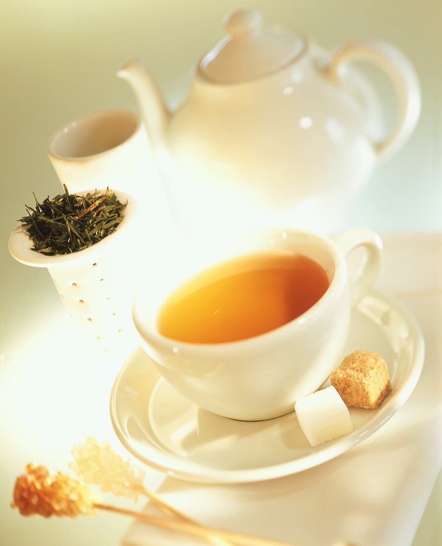 Green tea in white cup; sugar; teapot