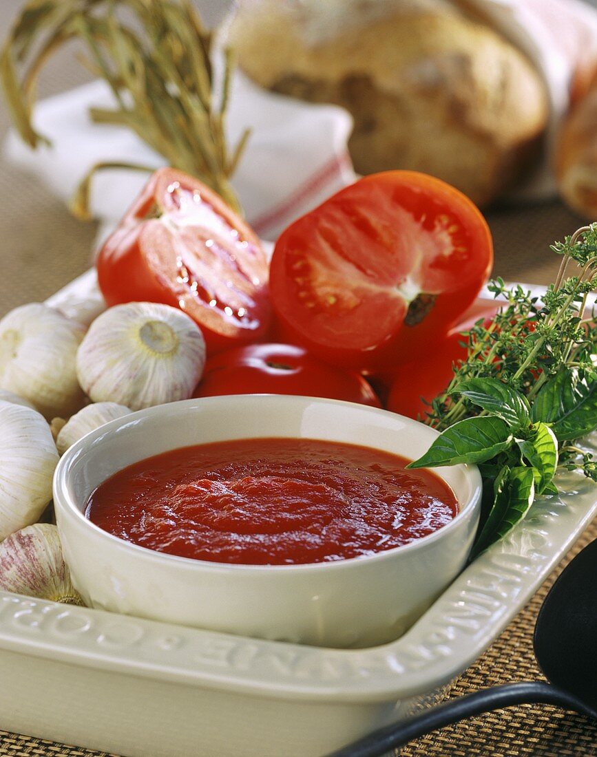 Tomato sauce in bowl, surrounded by ingredients