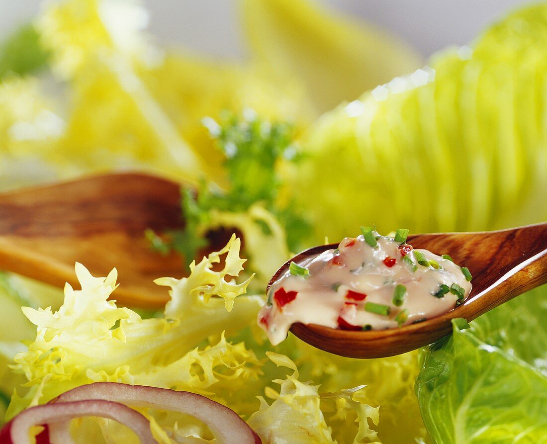 Salatdressing auf Löffel über gemischtem Blattsalat