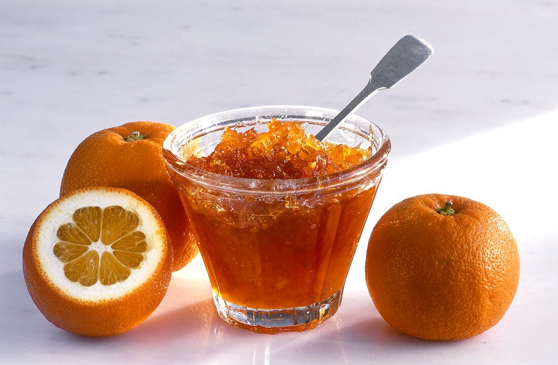 Orange marmalade in a glass dish and Seville oranges