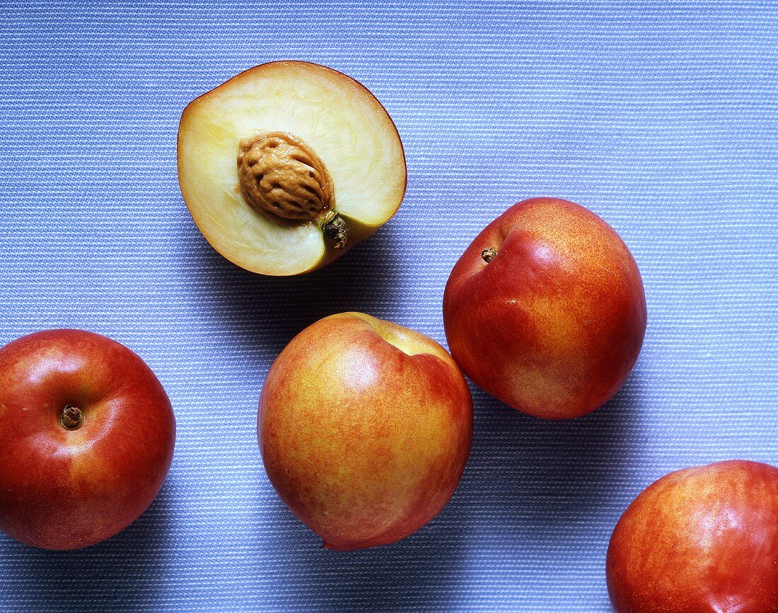 Half a nectarine with stone and three whole nectarines