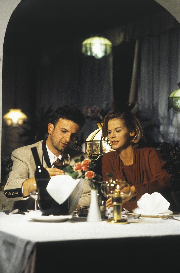 Paar im Restaurant sitzt am Tisch und trinkt Rotwein