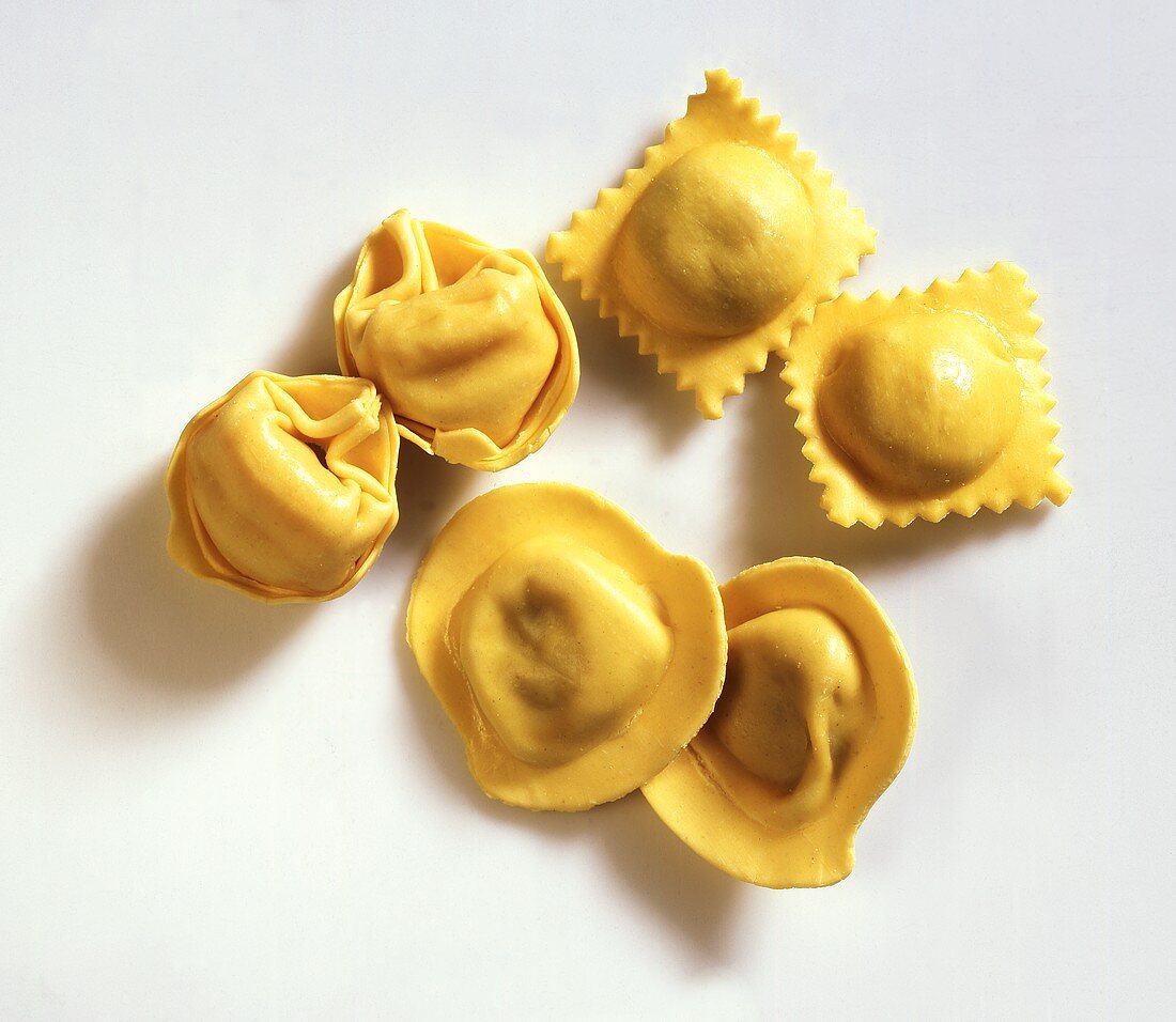 Ravioli and tortellini on light background