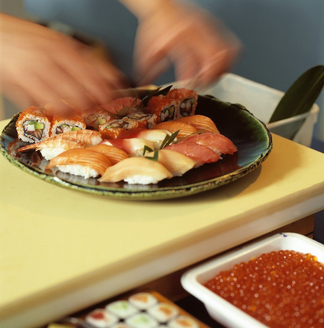 Hand legt Sushi auf einen Teller