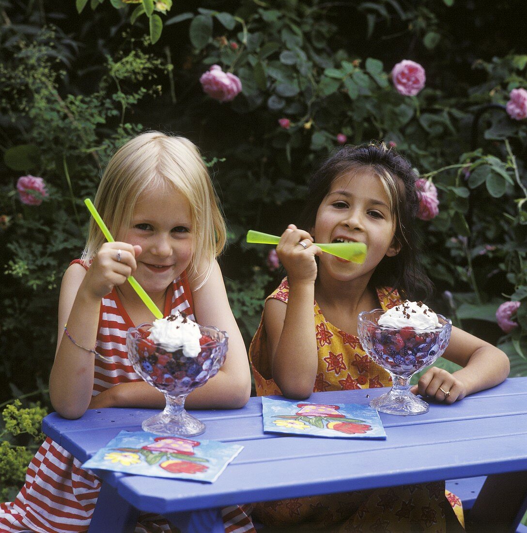 Zwei Mädchen essen Beeren-Dessert aus Bechern