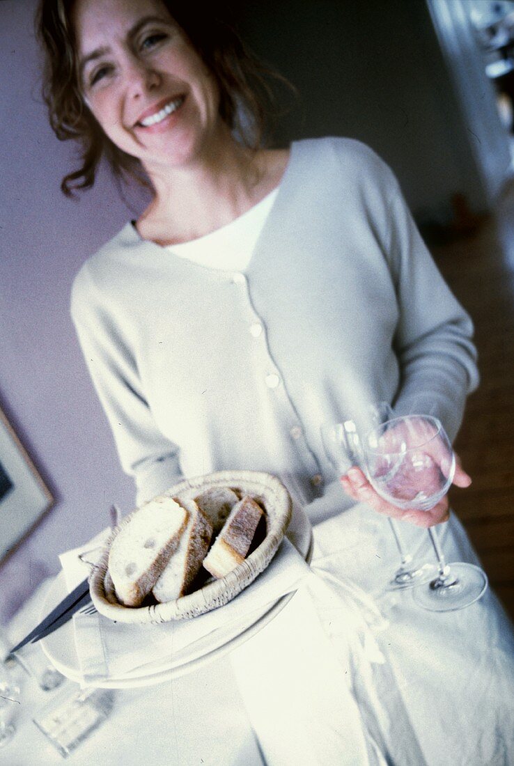 Frau hält Brotkorb und zwei Gläser