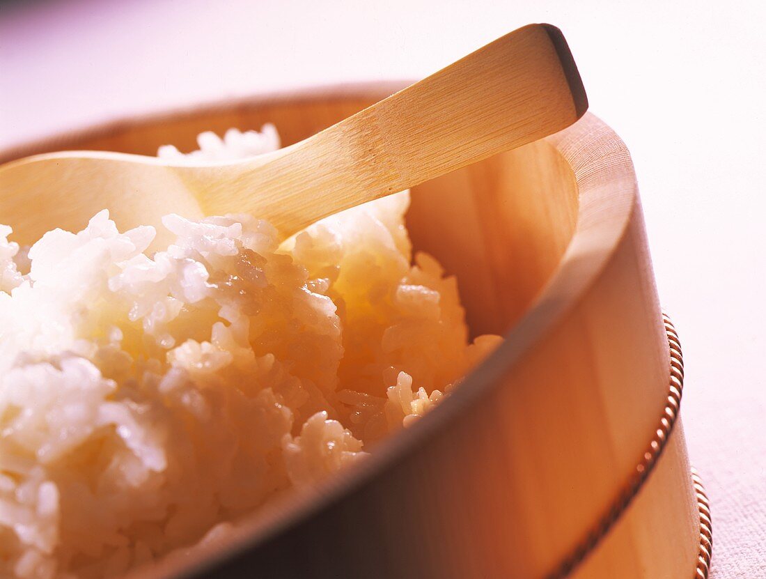 Sushi rice in wooden bowl with wooden spatula