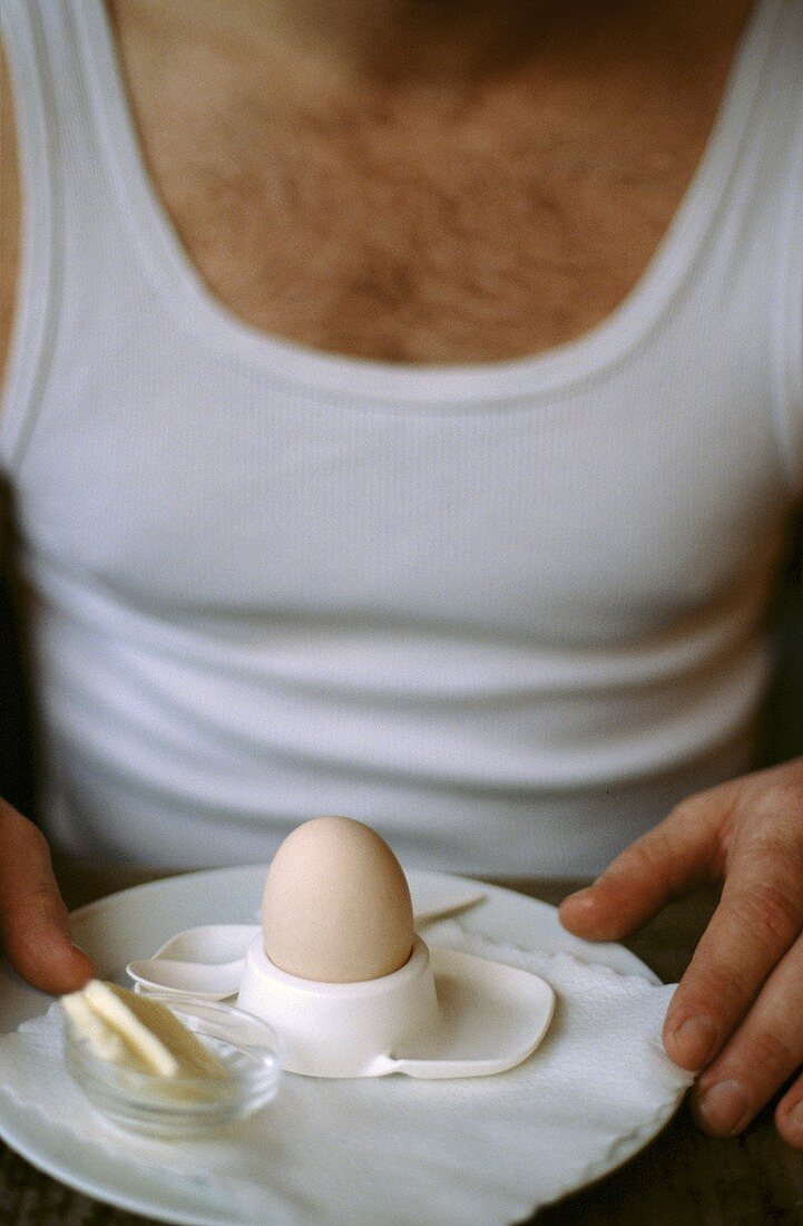 Mann im Unterhemd mit Frühstücksei