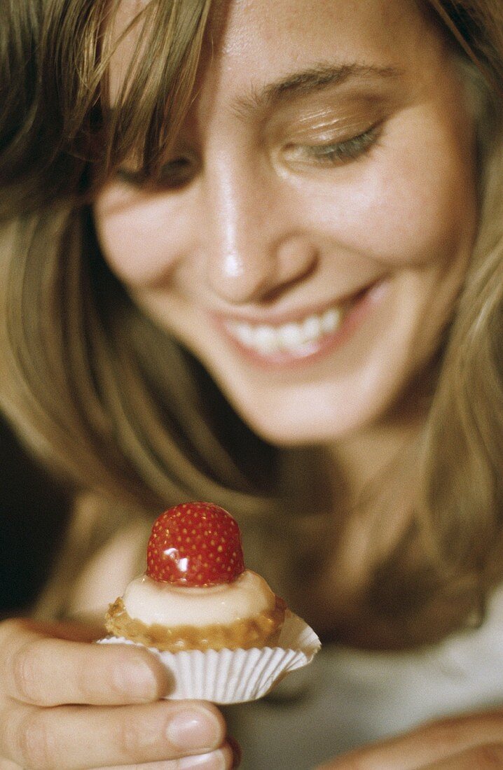 Lachende Frau hält ein Petit four