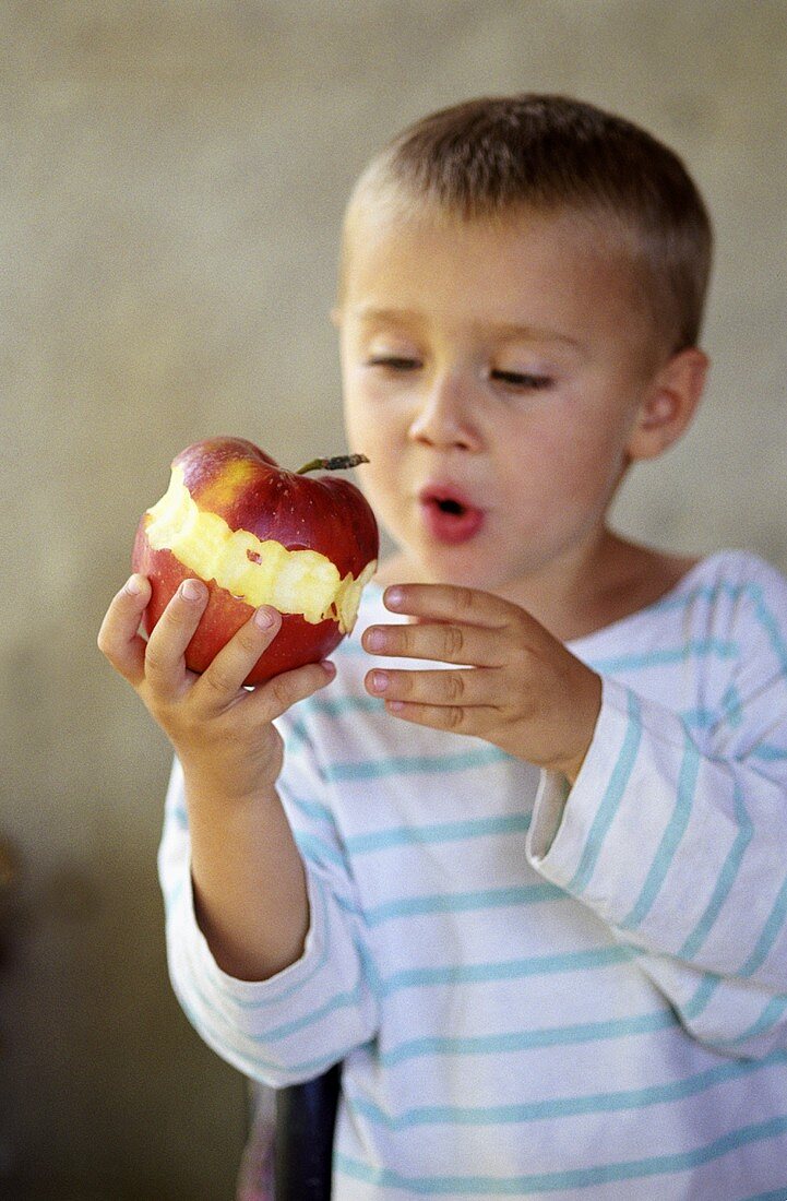 Small boy holding apple with bites taken 