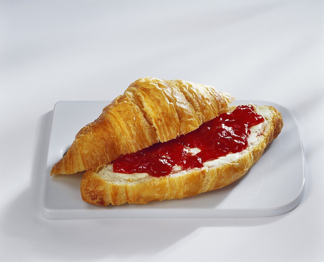 Croissant with butter and strawberry jam