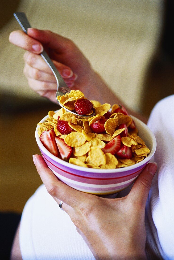 Pregnant woman eating cornflakes with strawberries