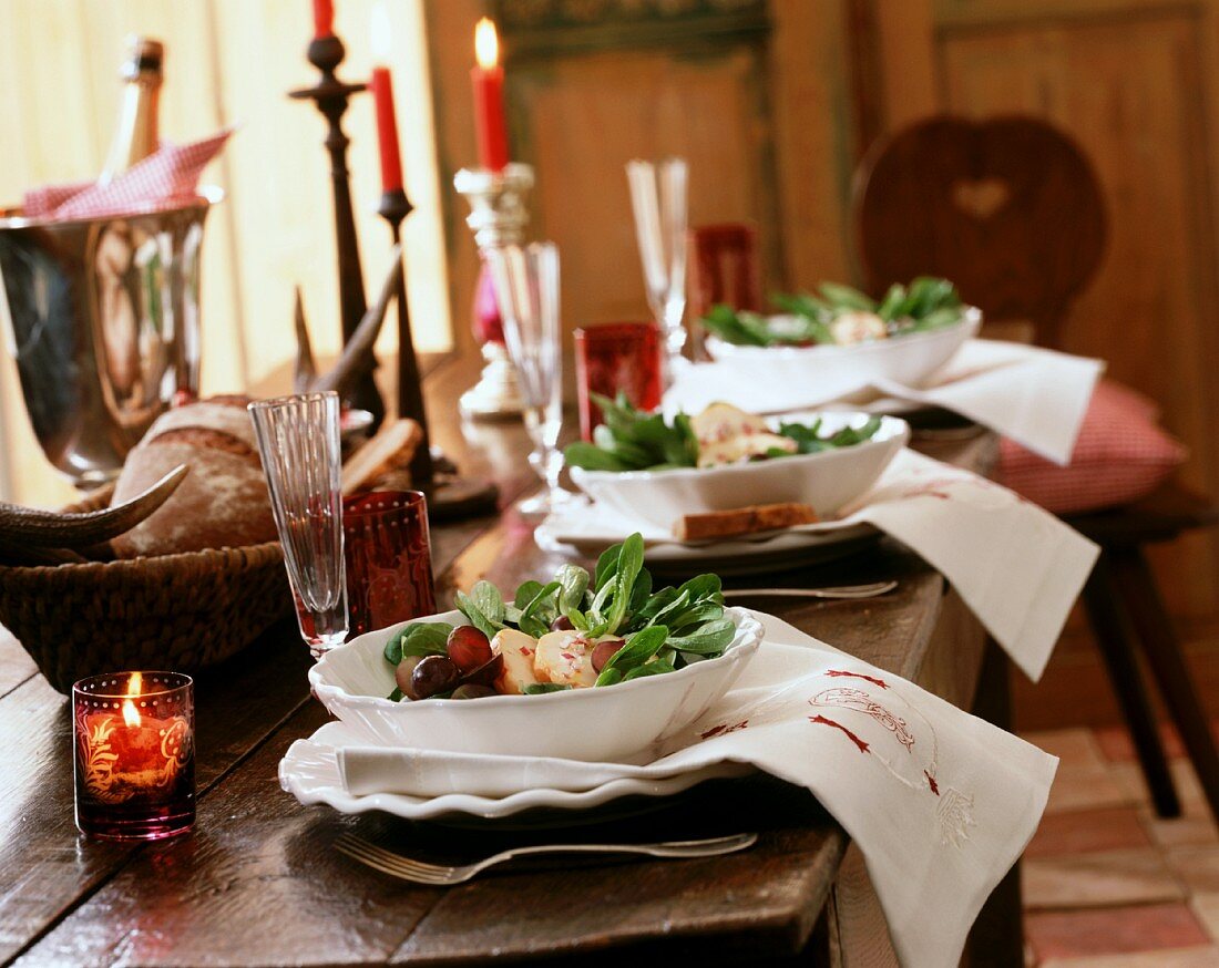 Rustikal gedeckter Tisch mit Salaten, Sekt und Kerzen