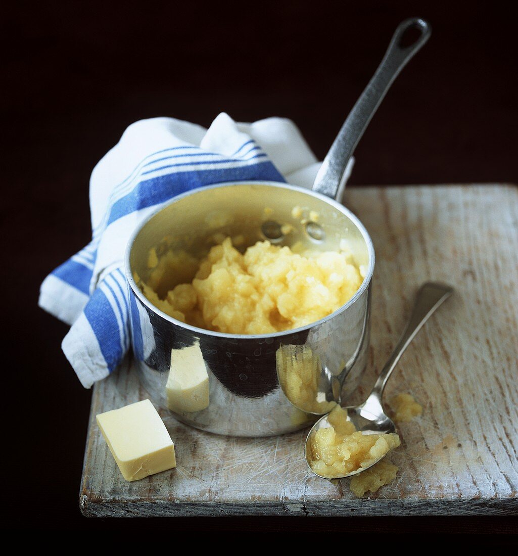 Mashed potato in pan; piece of butter; apple puree on spoon