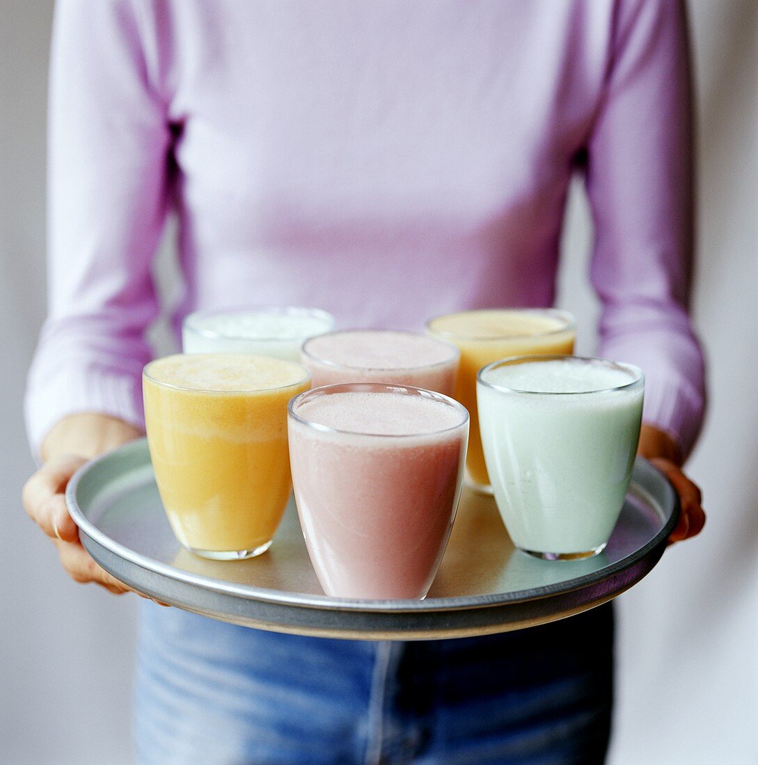 Woman serving tray of different smoothies