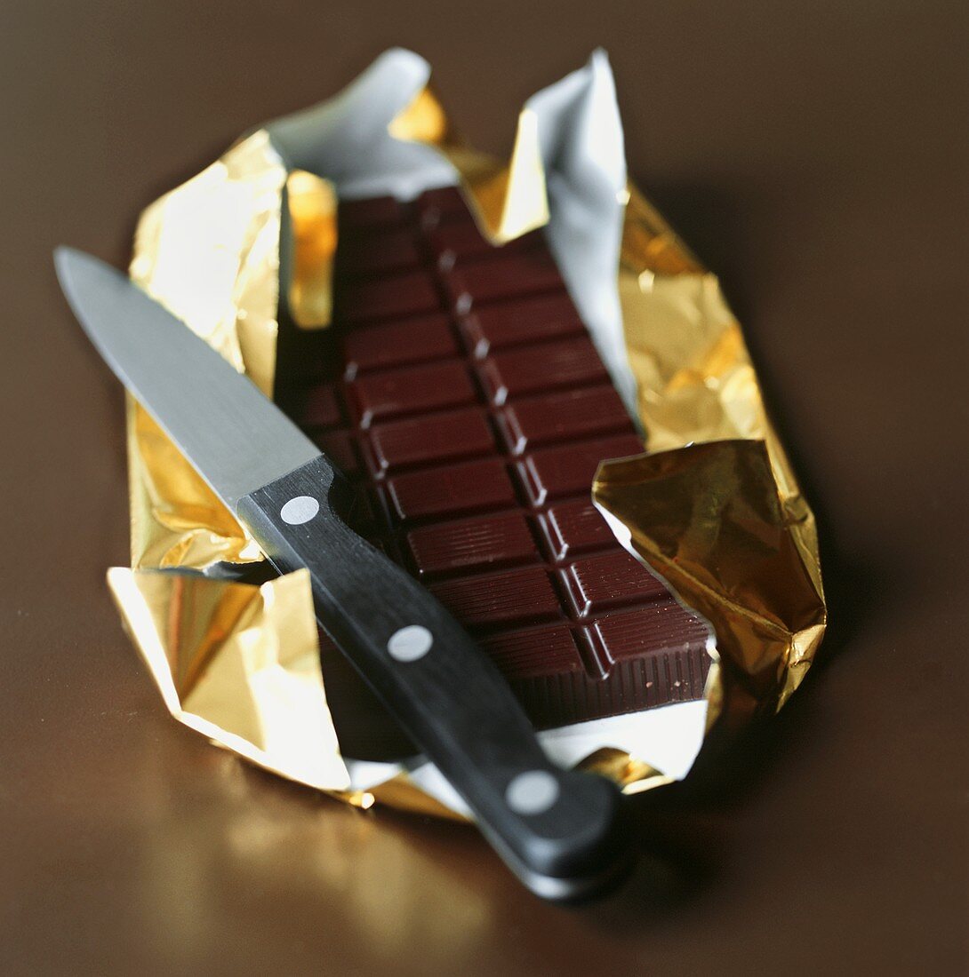 Bar of chocolate in gold foil with knife