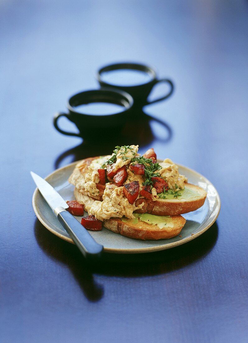 Spicy scrambled egg with chorizo on toasted bread; coffee