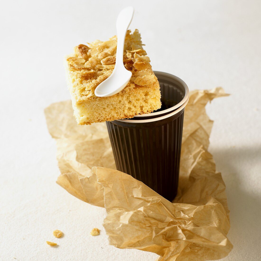 Piece of butter cake with flaked almonds on coffee mug