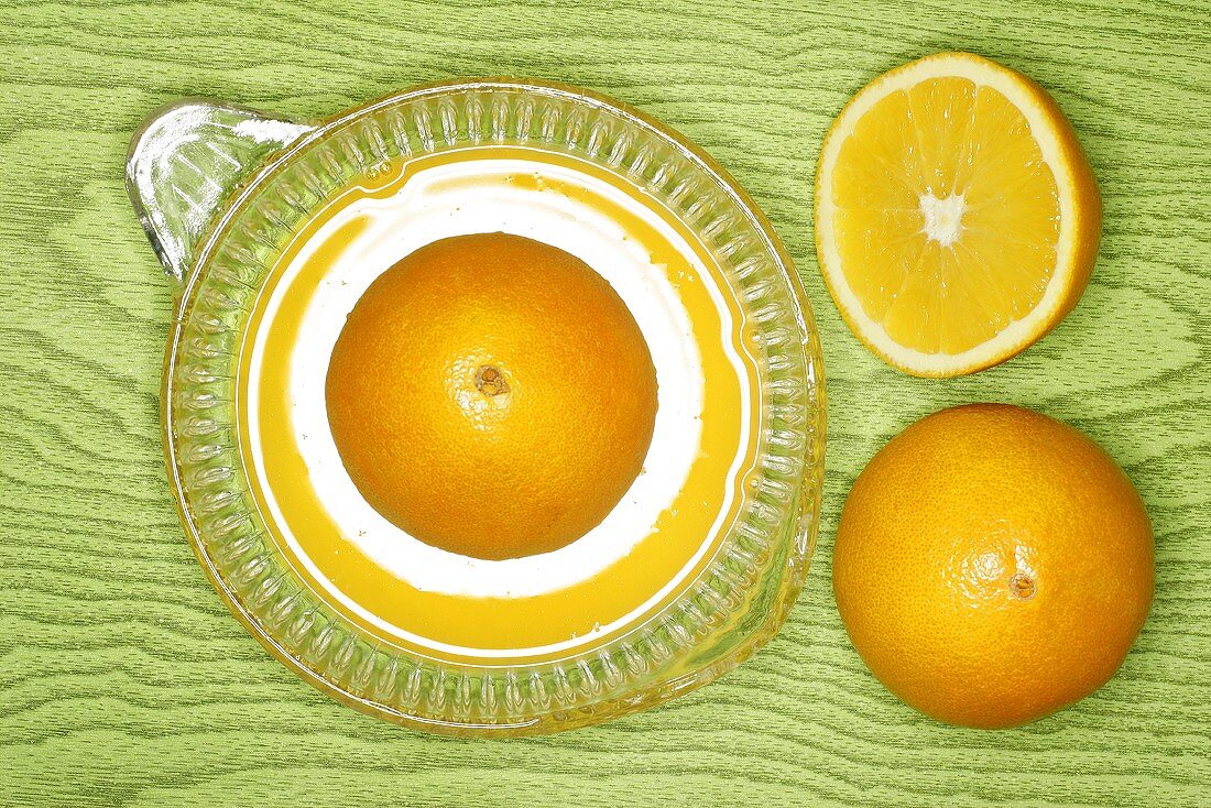 Oranges on lemon squeezer on green wooden background