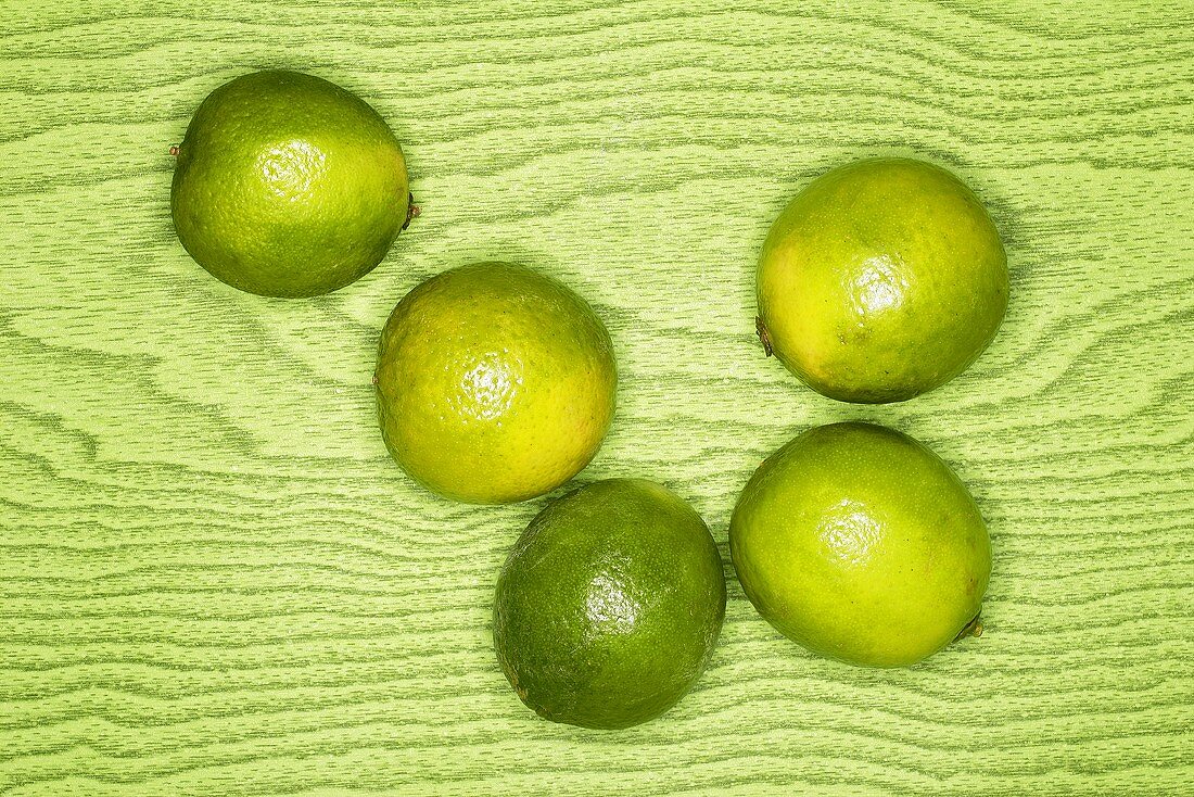 Limes on green wooden background