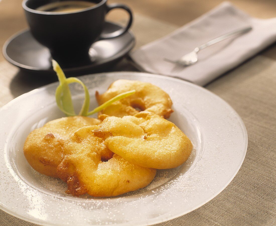 Apple fritters with sugar; cup of coffee