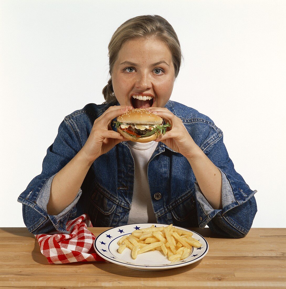 Modell isst Hamburger mit Pommes