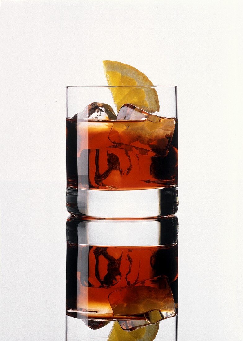 A glass of Campari with ice cubes and lemon slice