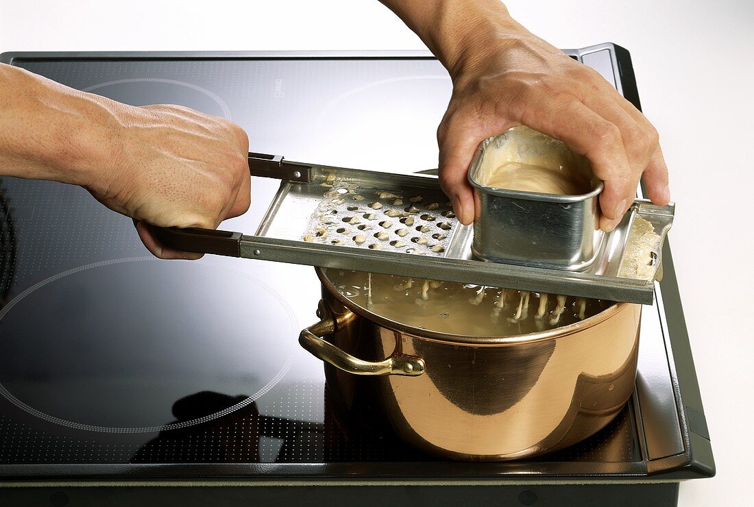 Making noodles (Spaetzle): shaving dough into boiling water