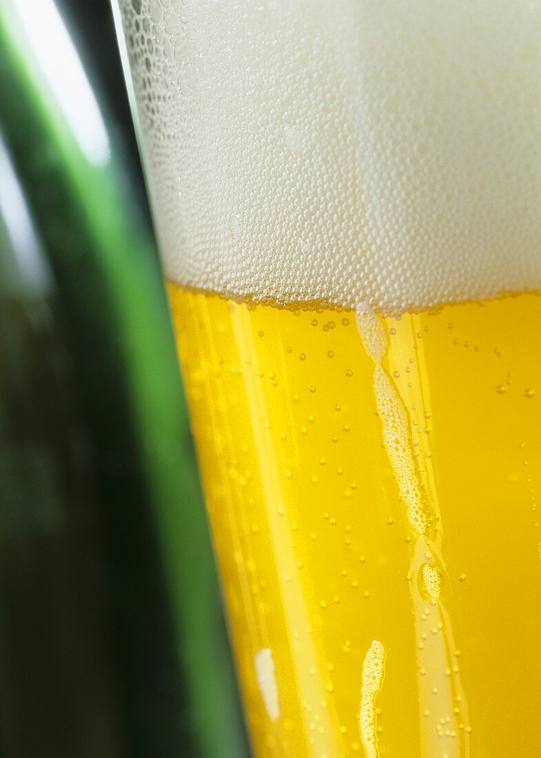 Ein Glas Pils neben einer Flasche