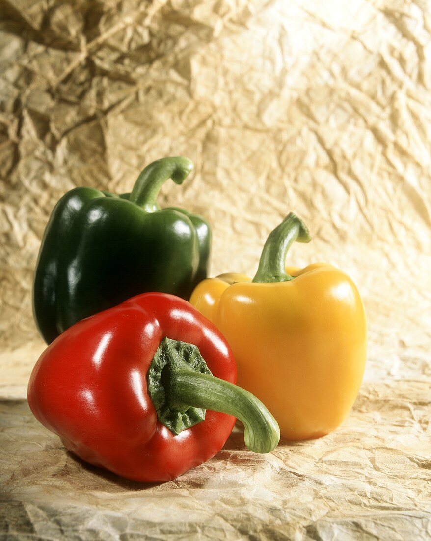 Three peppers (red, yellow, green) on paper