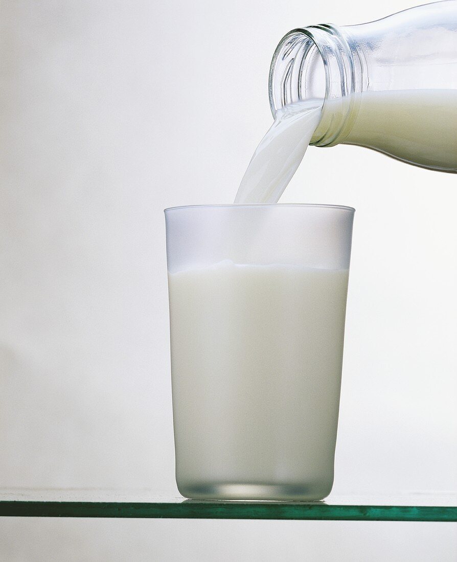 Milch aus der Flasche ins Glas gießen