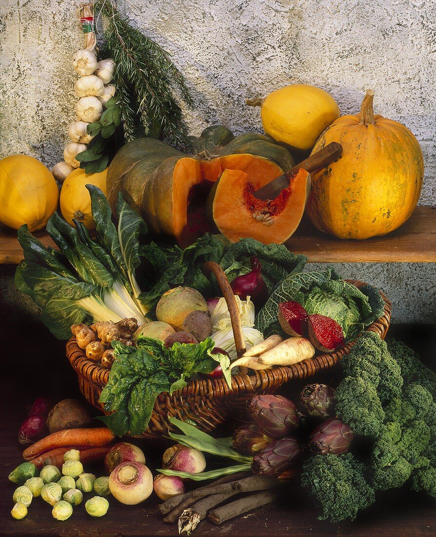 Verschiedene Gemüse im Weidenkorb, Kürbisse auf Holzregal