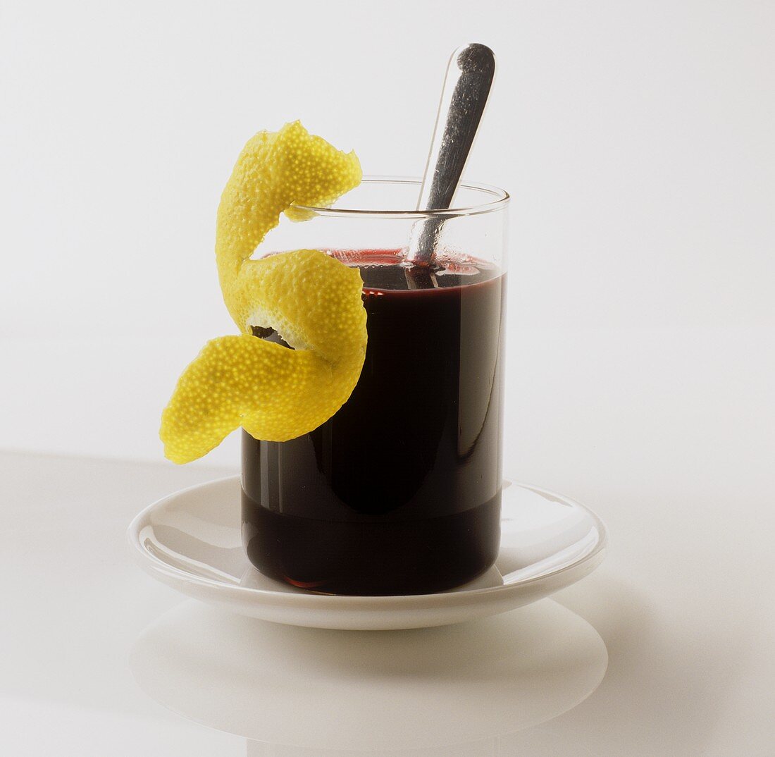 A glass of elderberry juice with lemon rind