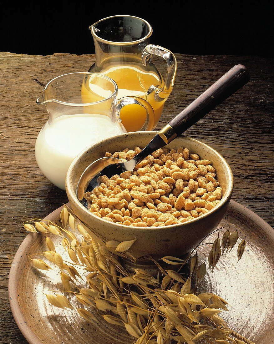 Eine Schüssel Cornflakes, eine Kanne Milch und Saft