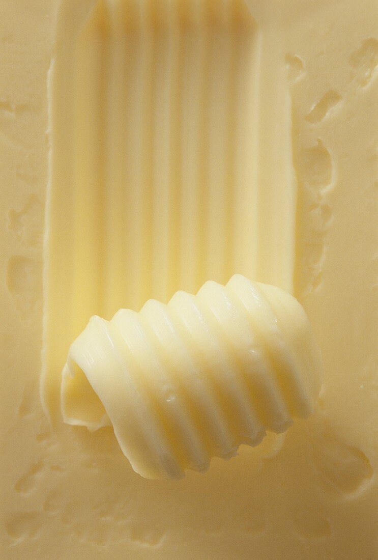 A piece of butter with butter curls (close-up)
