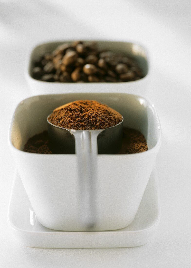 Coffee powder with spoon and coffee beans in bowls