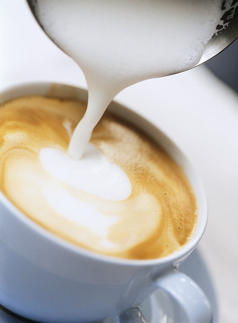 Pouring milk foam on to cappuccino
