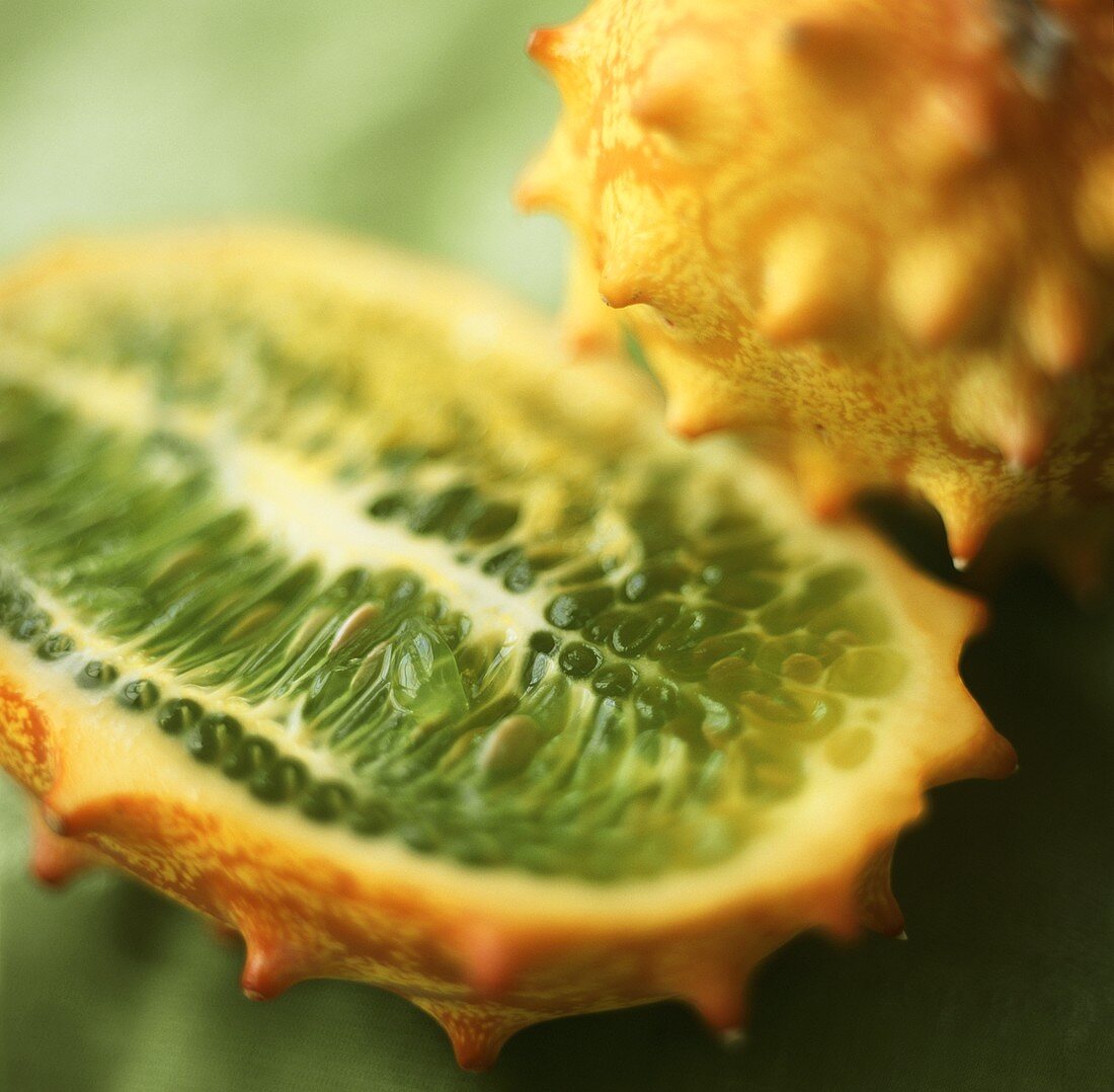 Half and whole kiwano on a green background