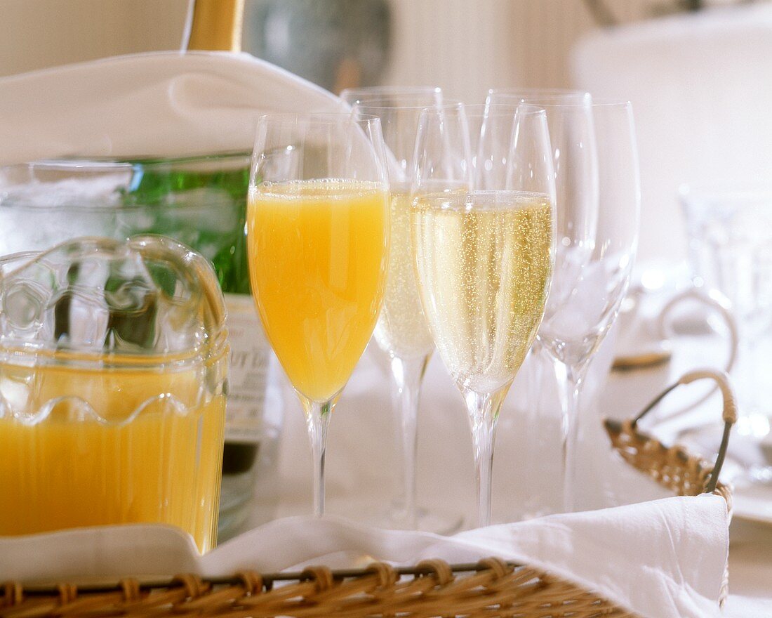 Full & empty champagne glasses & orange juice on cane tray
