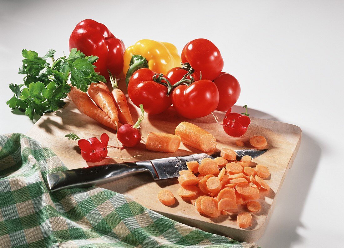 Möhren, Tomaten und Paprika mit Messer auf einem Brett