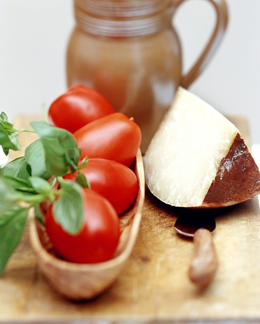 Fresh tomatoes, basil and piece of cheese; terracotta jug