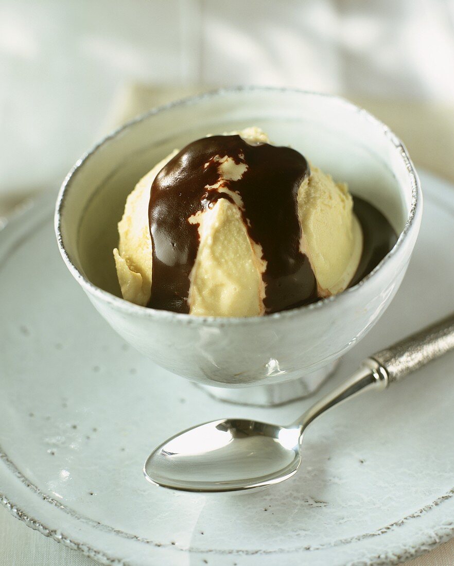 Vanilleeis mit Schokoladensauce in weißem Schälchen