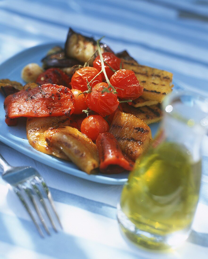 Grilled vegetables on blue plate; olive oil