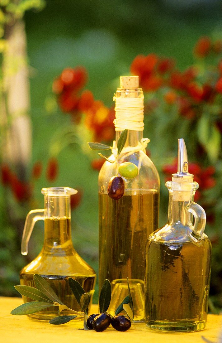 Verschiedene Flaschen mit Olivenöl auf Tisch im Garten