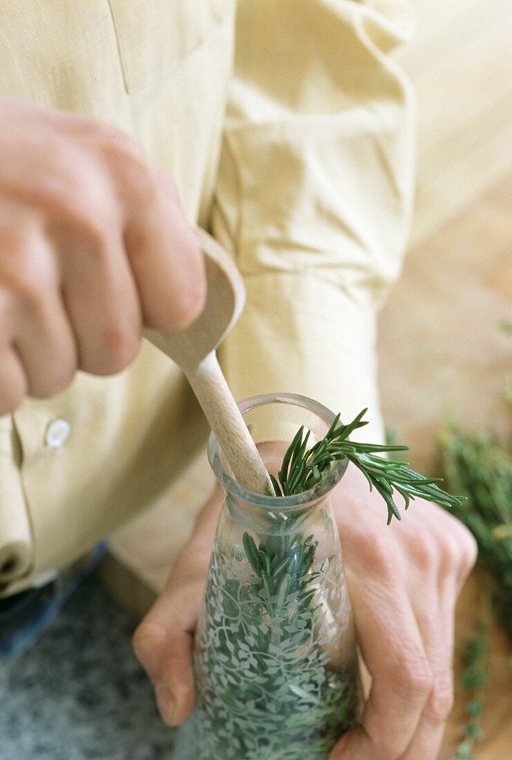 Preparing herb oil: pushing herbs into bottle