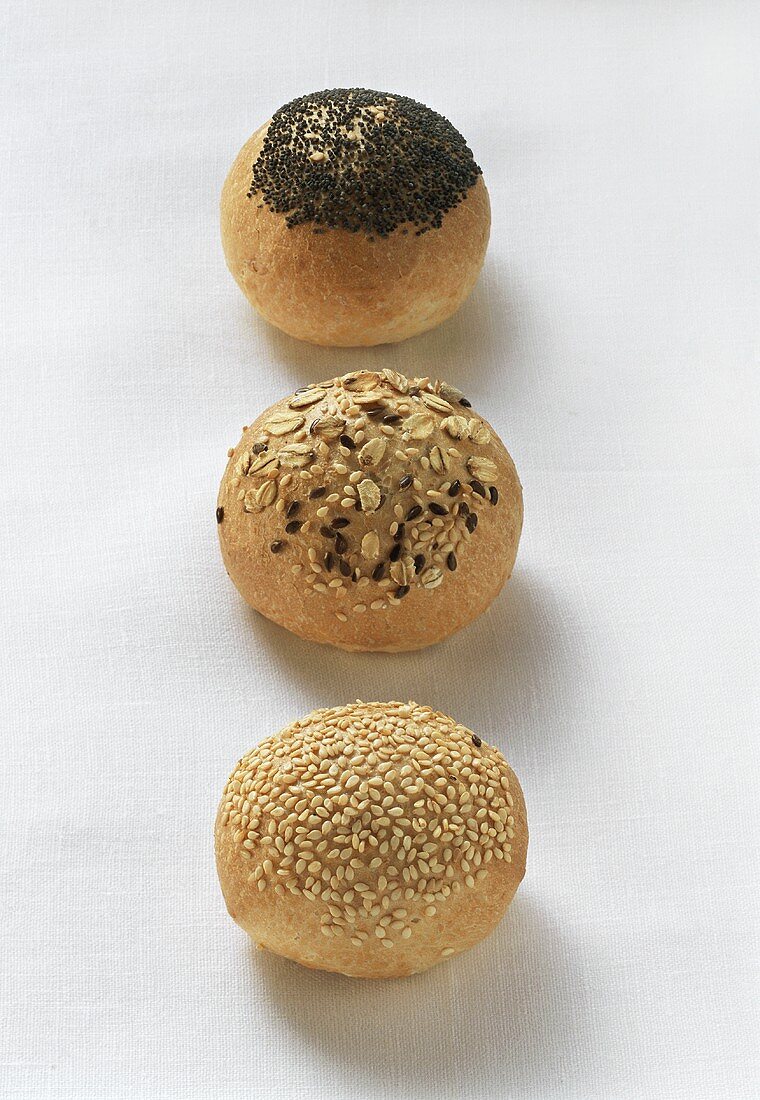 Three bread rolls with sesame, rolled oats and poppy seeds
